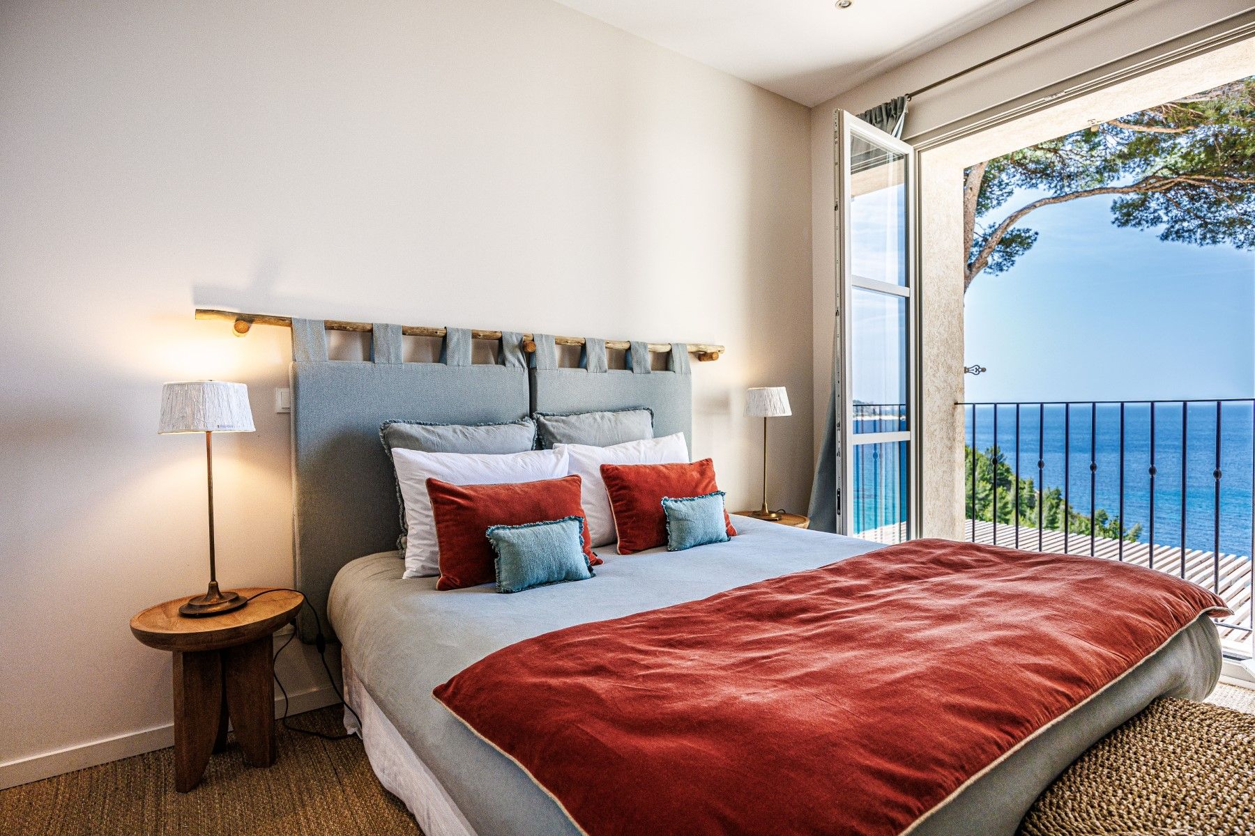 Double bedroom with red throw and sea view balcony doors at Villa Florie in Côte d'Azur