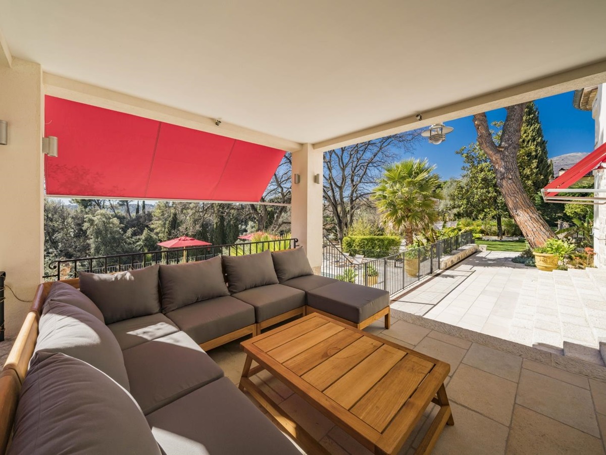 Shaded outdoor lounging area overlooking the pool and gardens of Villa Malvan, luxury villa in the Cote d'Azur region of France