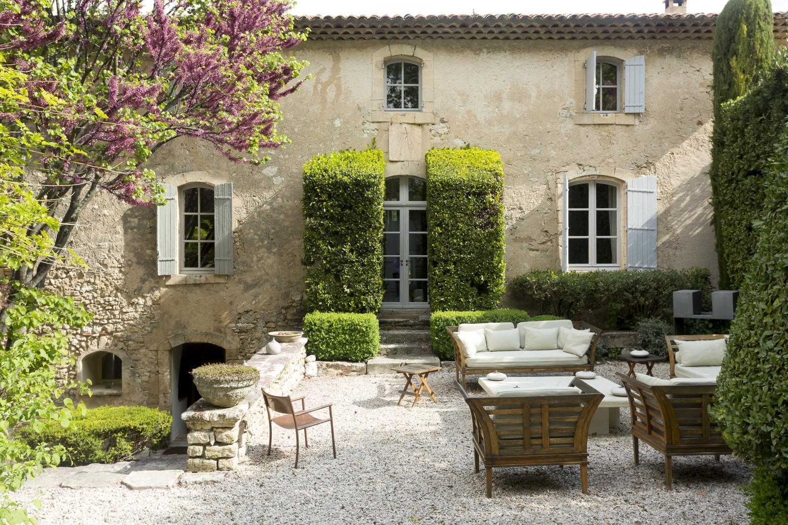 Facade of villa and gardens with trees, blossom, hedges and maze at Bastide Luberon in Provence, France