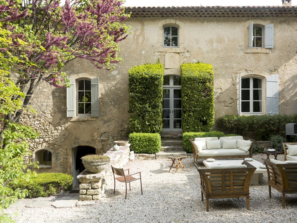 Facade of villa and gardens with trees, blossom, hedges and maze at Bastide Luberon in Provence, France