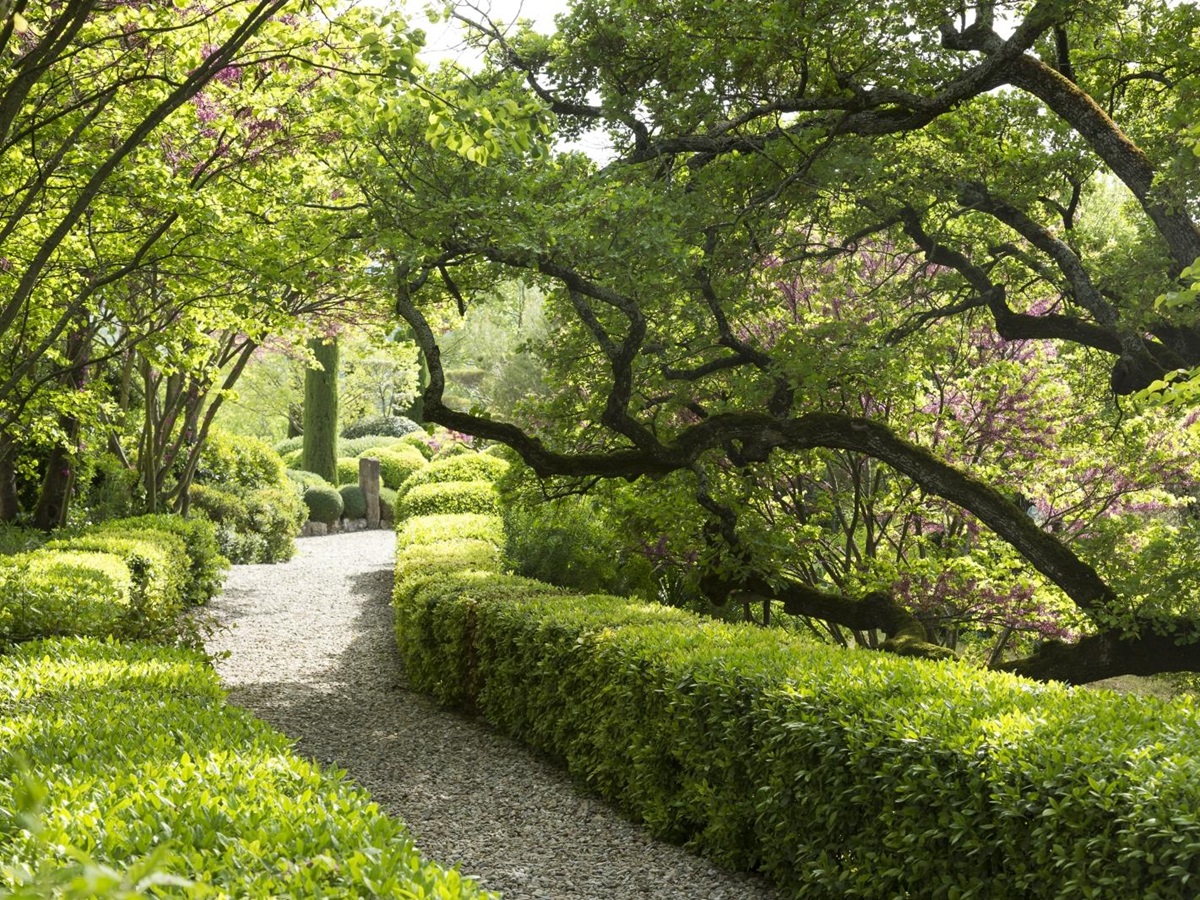 Garden with trees, hedges, flowers and pathway at Bastide Luberon in near Bonnieux Provence, France