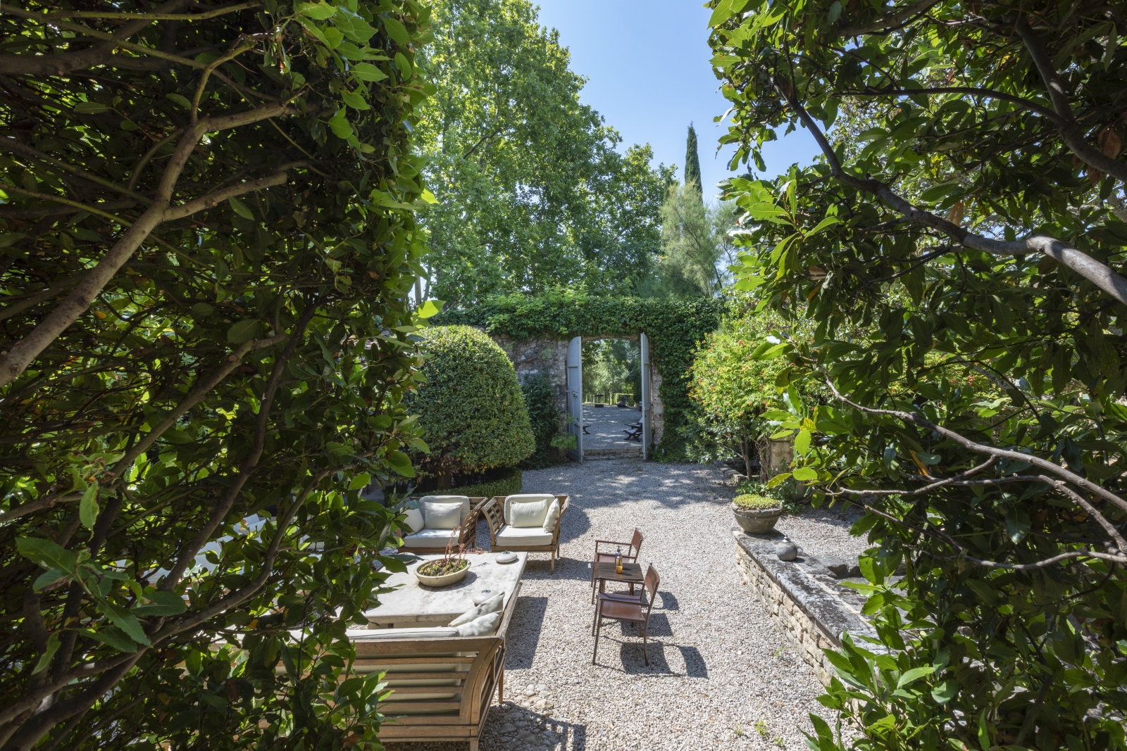 Gardens with hedges, trees and comfy seating area at Bastide Luberon in Provence, France
