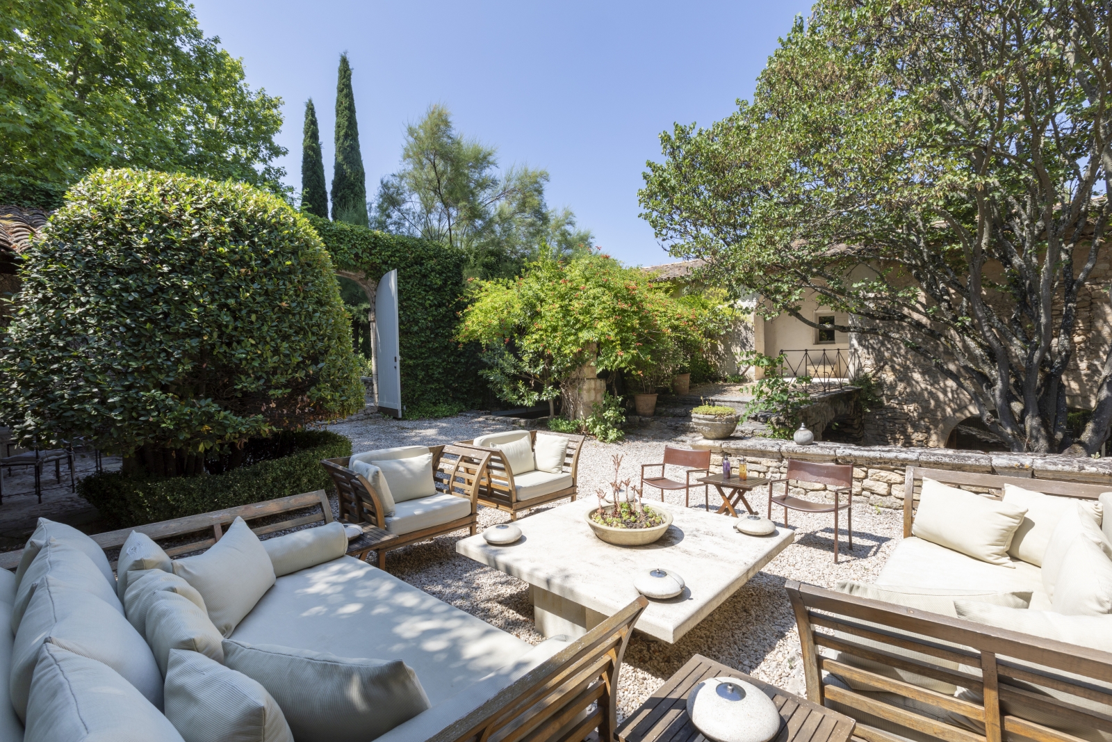 Comfy seating area with sofas, armchairs, coffee table and trees at Bastide Luberon in Provence, France