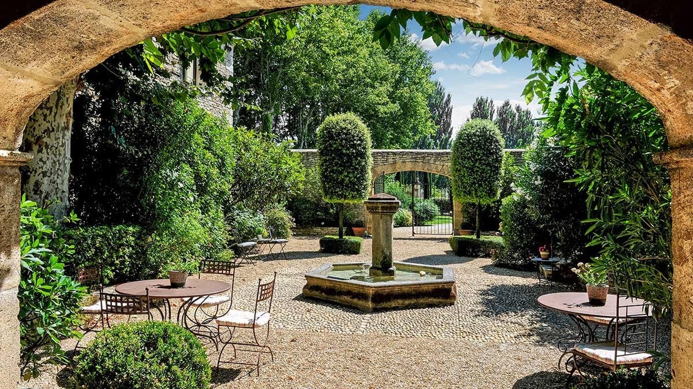 Courtyard with small tables and chairs and stone arch Bastide sur la Sorgue in Provence
