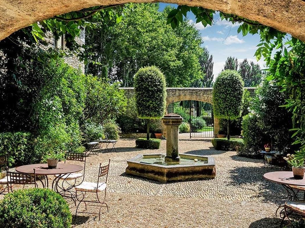 Courtyard with small tables and chairs and stone arch Bastide sur la Sorgue in Provence