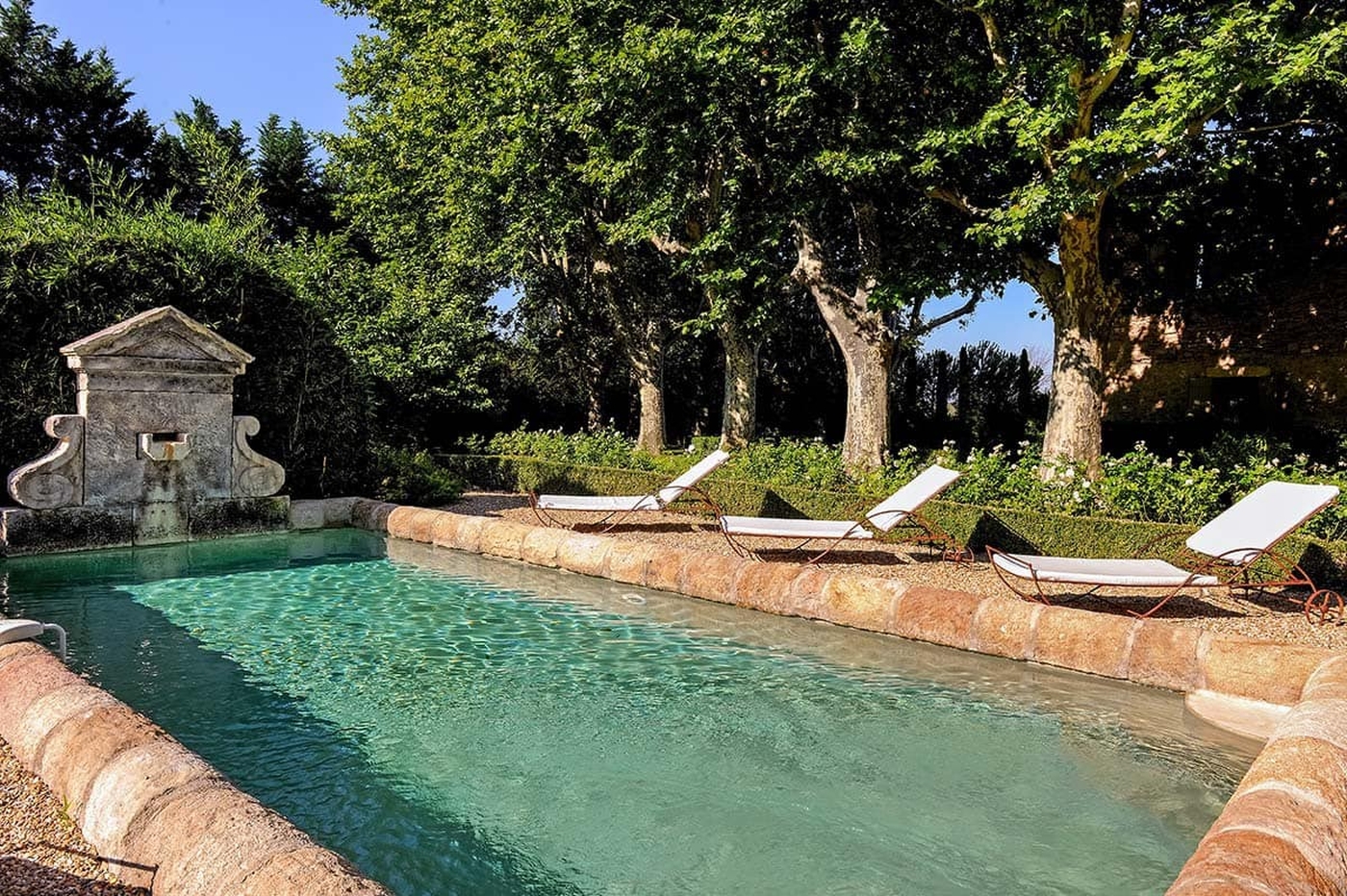 Swimming pool with stone statue and sun loungers at Bastide Sur La Sorgue in Provence 