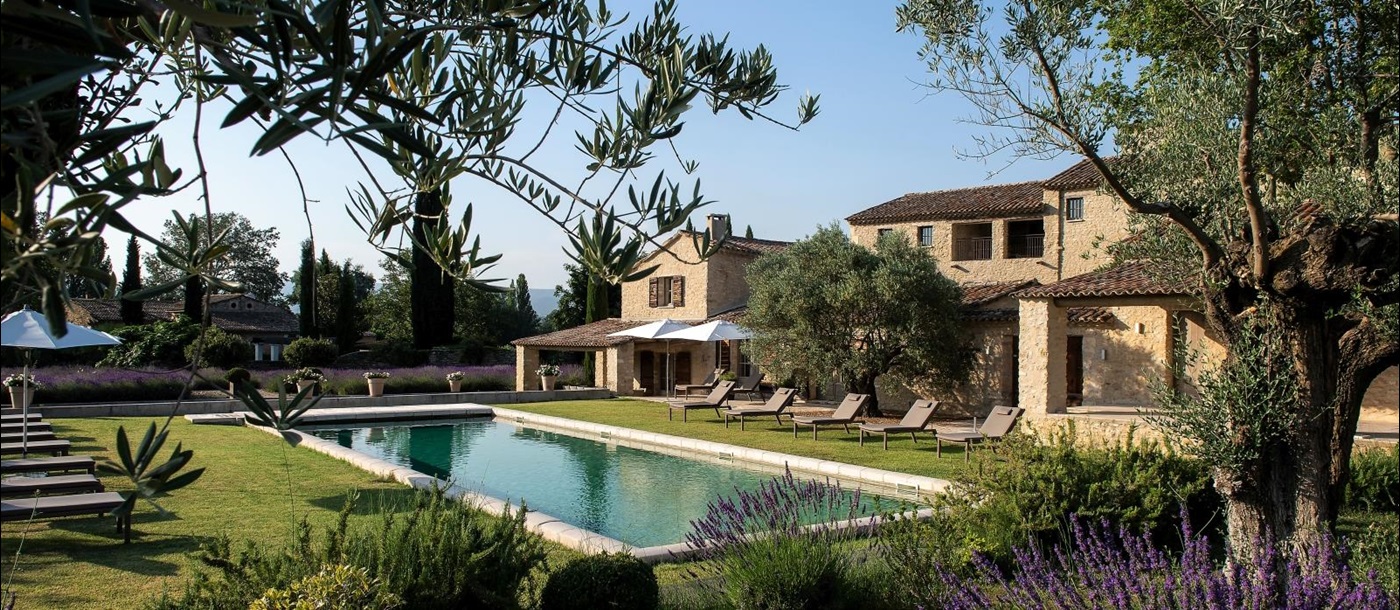 Garden and pool area with lavender, olive trees and sun loungers at Domaine des Baumettes in Provence, France