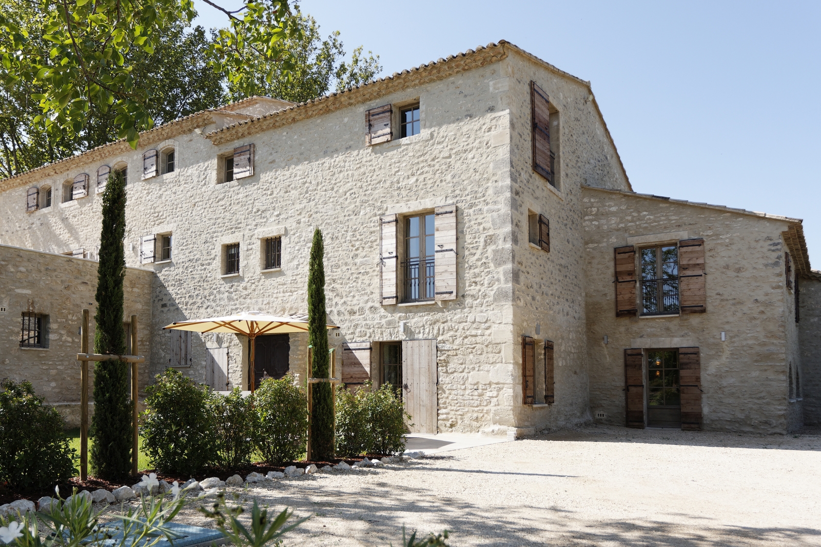 Facade of villa with plants, small garden and umbrella at Domaine des Baumettes in Provence, France