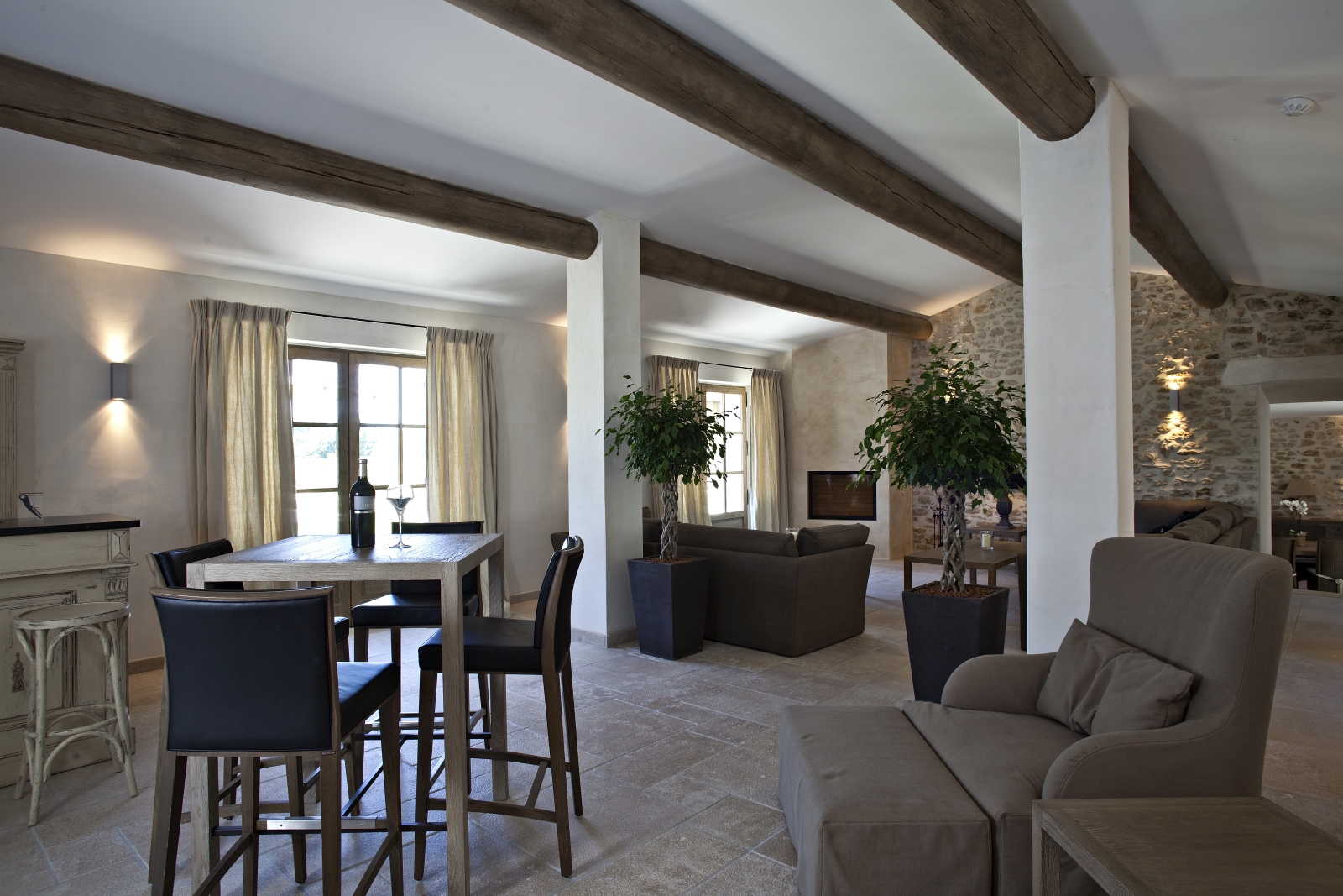 Living room with sofas, plants, armchair, table, stools and bar at Domaine des Baumettes in Provence, France
