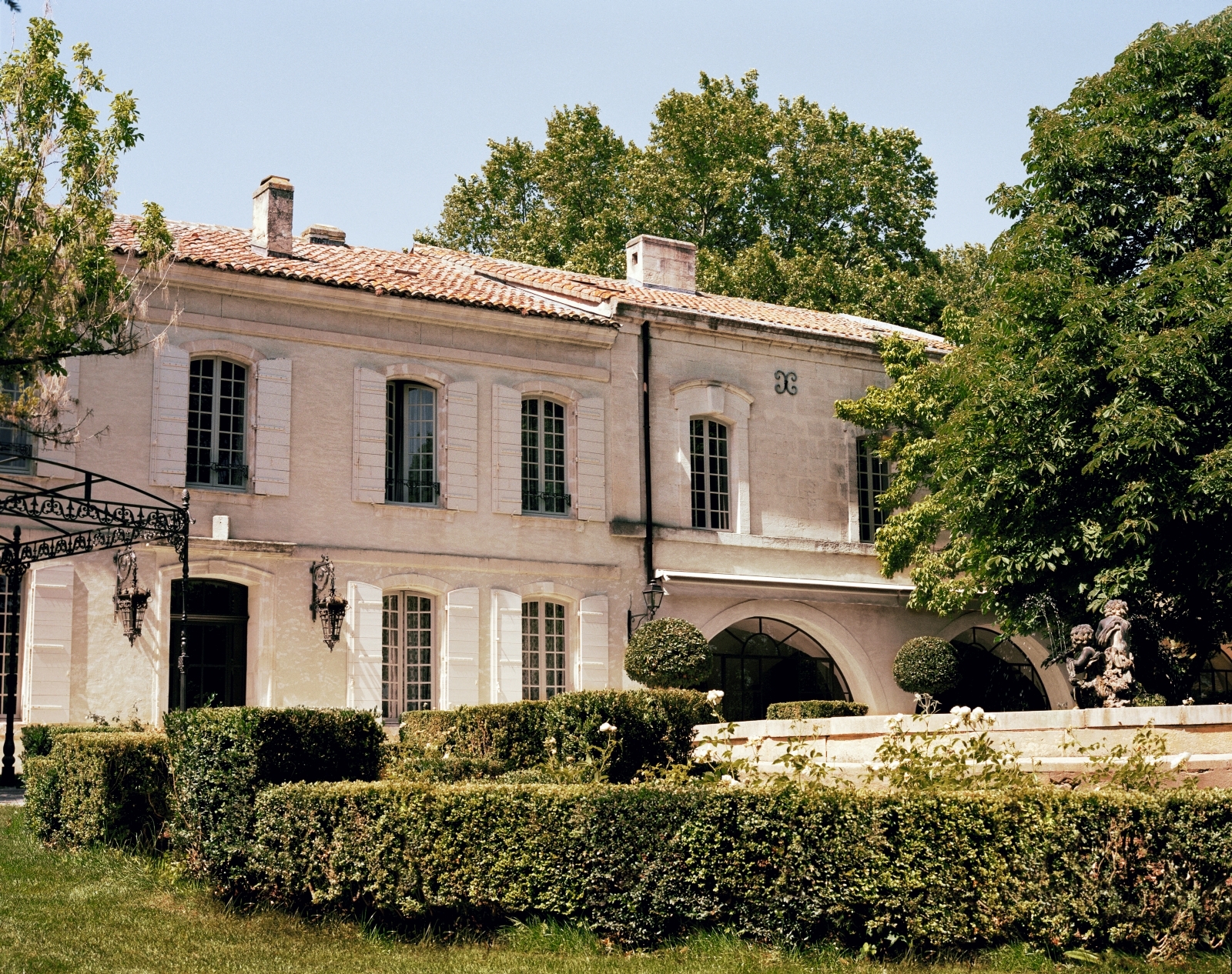 Pale stone exterior with white window shutters of Le Mas de Liliana, a luxury villa in Provence