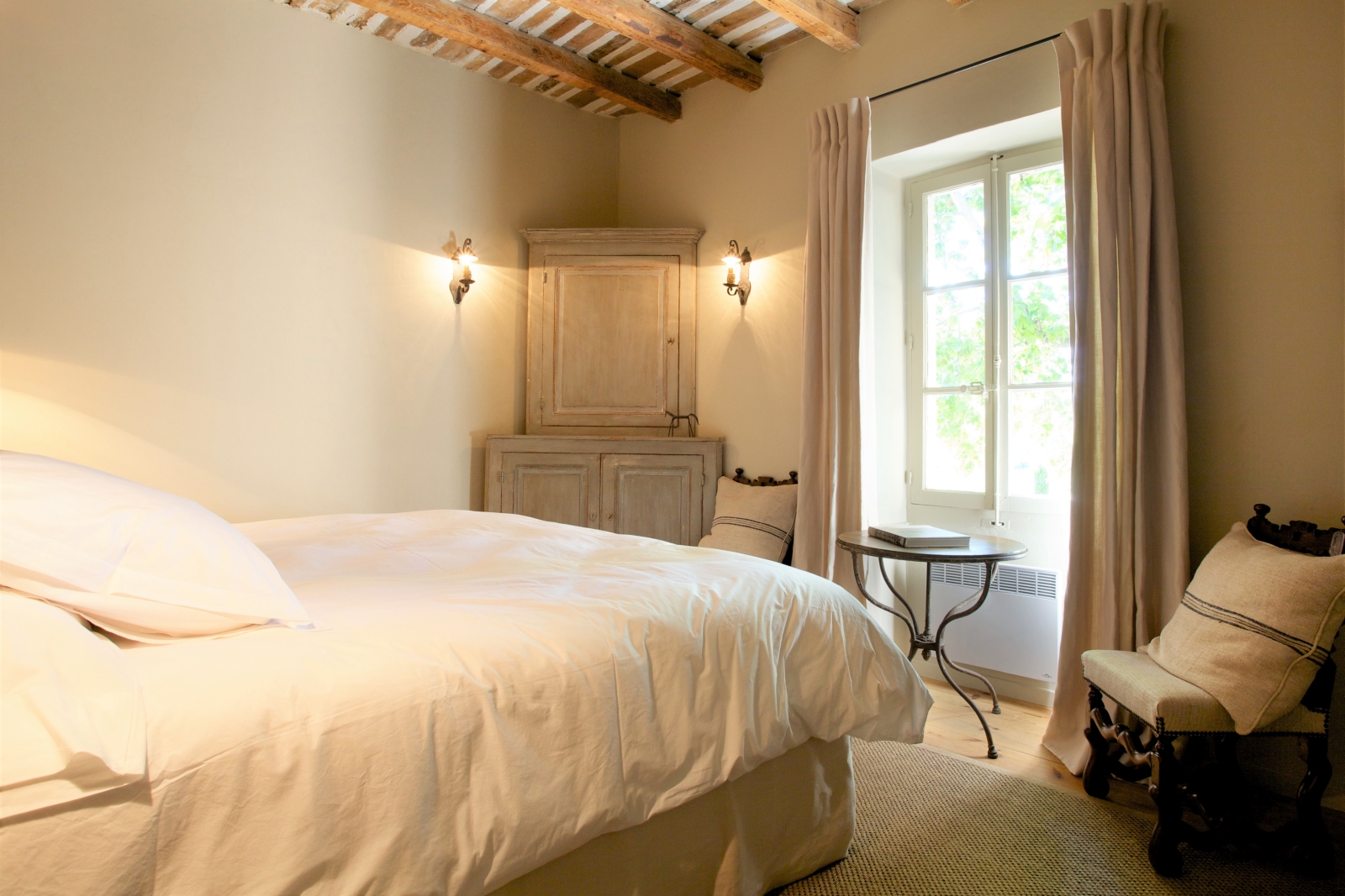Bedroom with double bed, armchair, table, chair, window and cabinet at Le Pont Romain in Provence, France