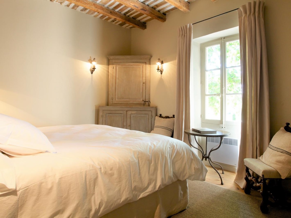 Bedroom with double bed, armchair, table, chair, window and cabinet at Le Pont Romain in Provence, France