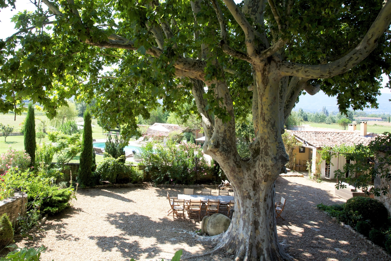 Aerial view of terrace with table, chairs and tree and garden with pool at Le Pont Romain in Provence, France