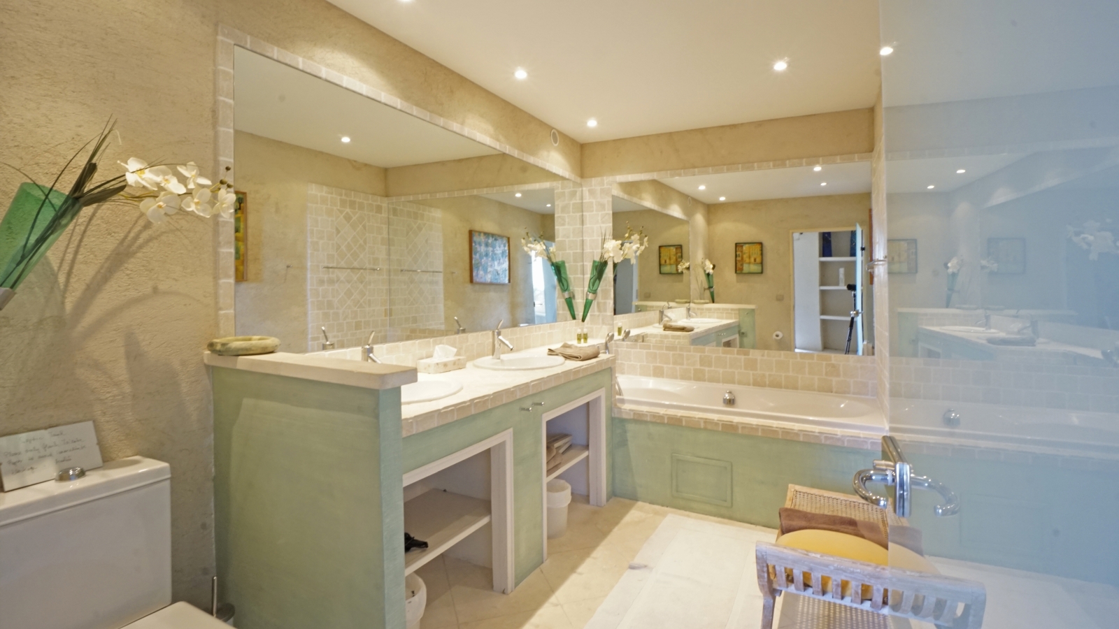 Bathroom with double sinks, large mirrors, bathtub and orchids at Les Rochers in Provence, France