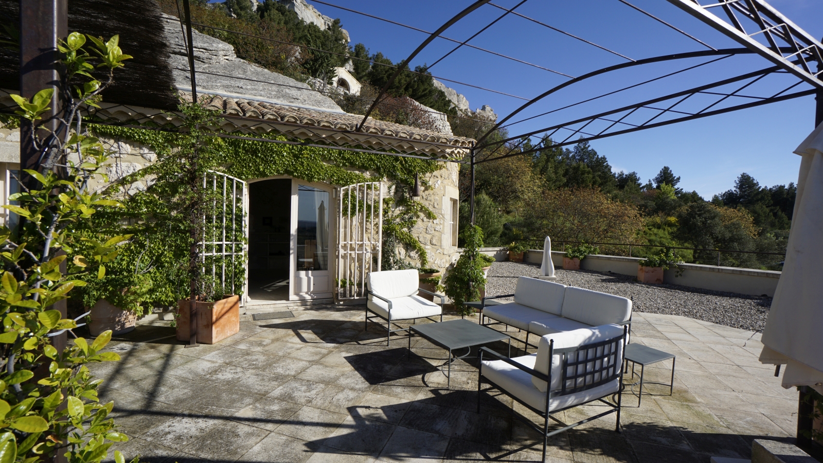 Terrace with comfy chairs, coffee tables, plants and French doors into villa at Les Rochers in Provence, France