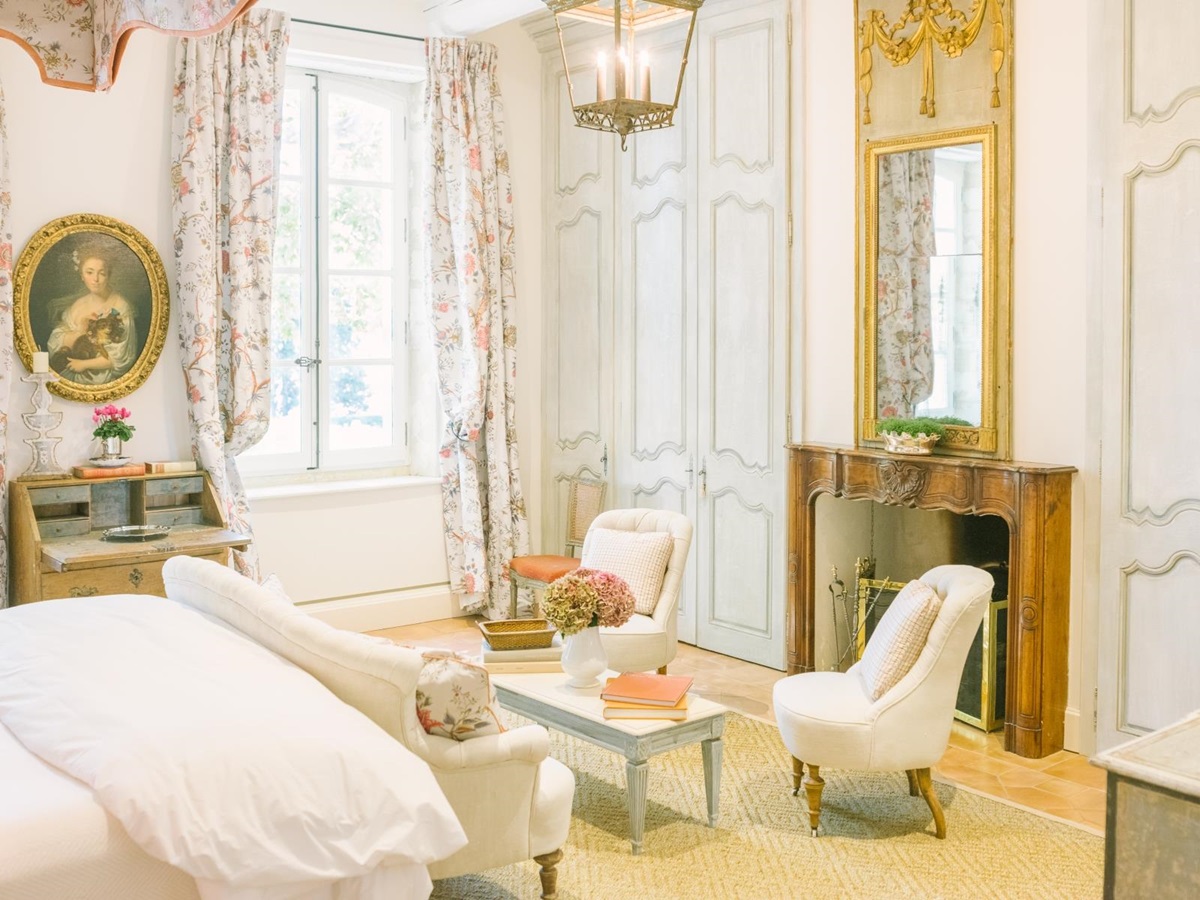 Bedroom with double bed, sofa, armchairs, coffee table, fireplace and mirror at Mas de la Motte in Provence, France