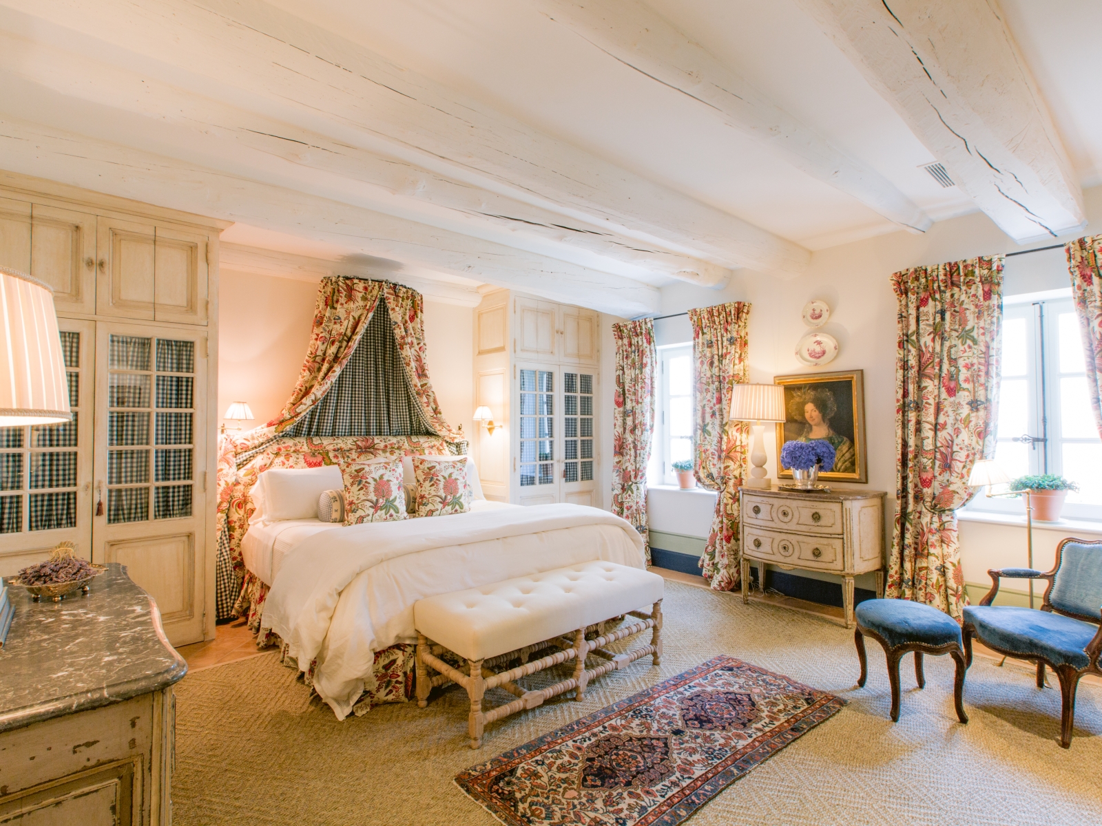 Bedroom with double bed, lamps, armchair, cabinets and painting at Mas de la Motte in Provence, France
