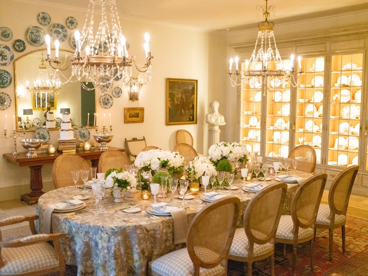 Dining room with chandeliers, candles, flowers, cabinets, mirror and painting at Mas de la Motte in Provence, France