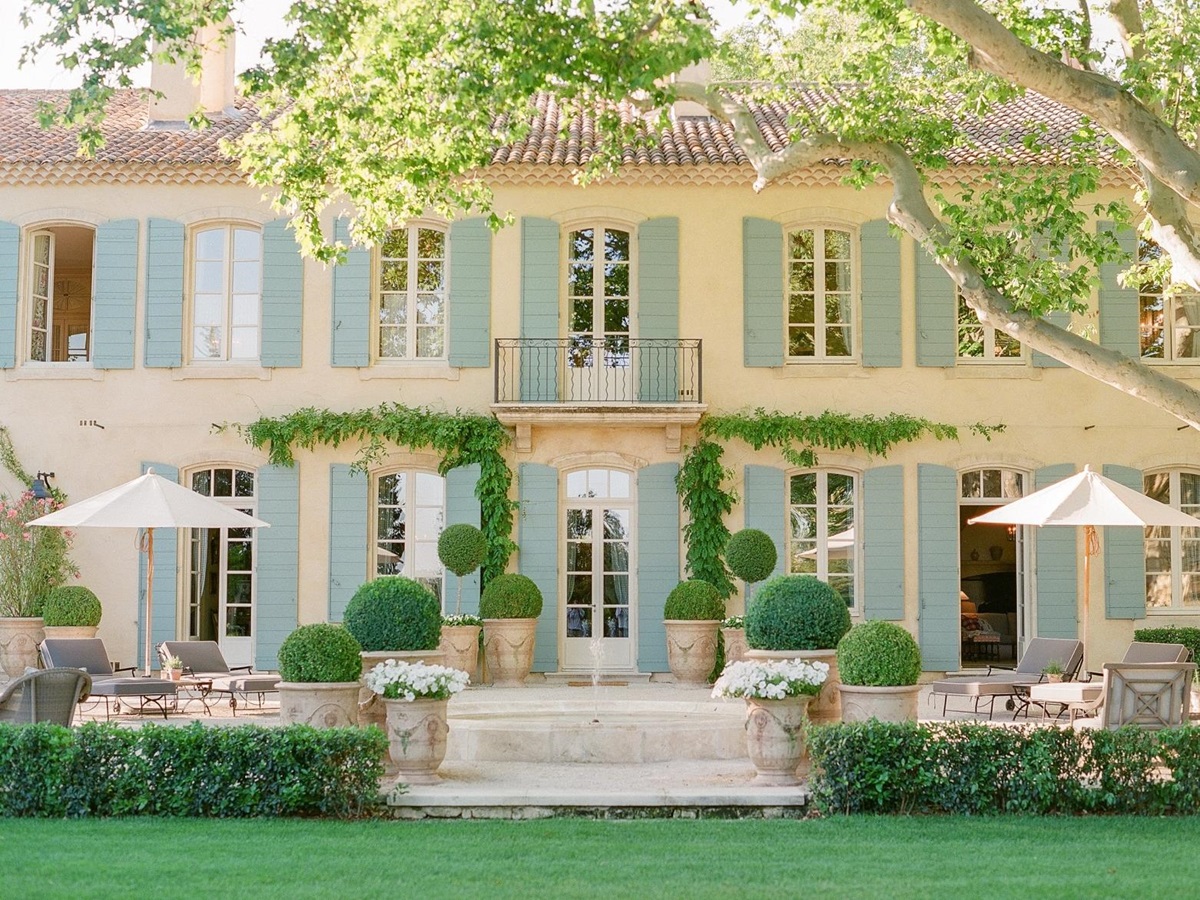 Back of villa and patio with sun loungers, umbrellas, flowers and plants at Mas de la Motte in Provence, France