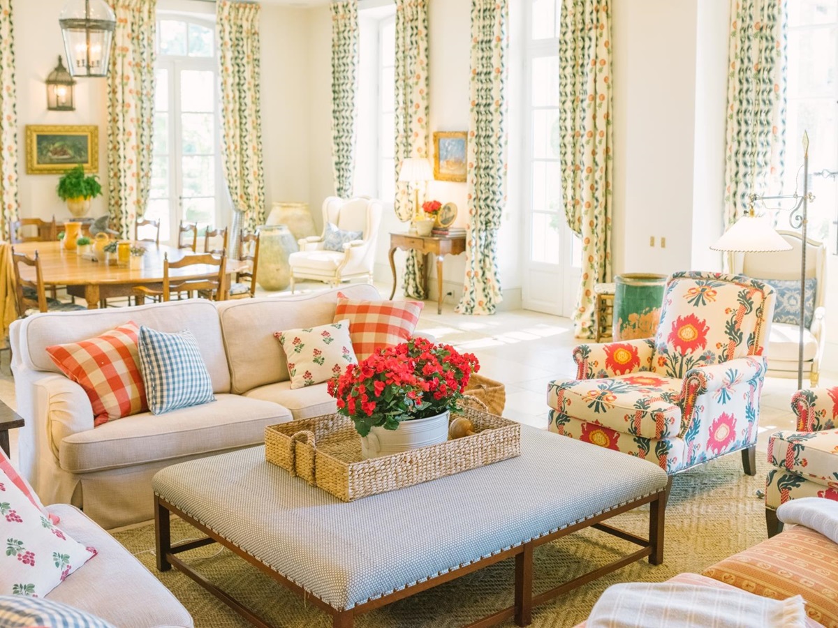 Family room with sofas, dining table, armchair, lamps, patterned curtains and flowers at Mas de la Motte in Provence, France