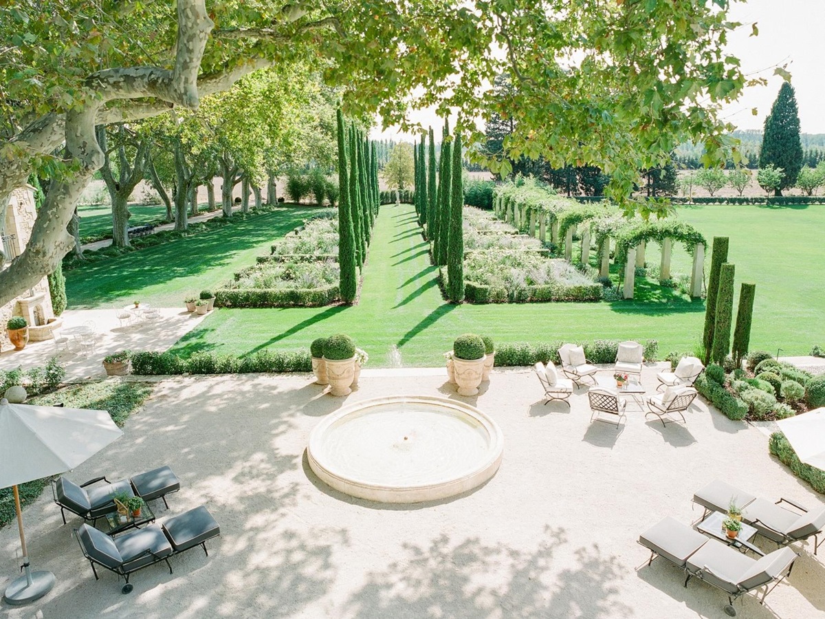 Patio next to garden with sun loungers, fountain, umbrellas, table and chairs at Mas de la Motte in Provence