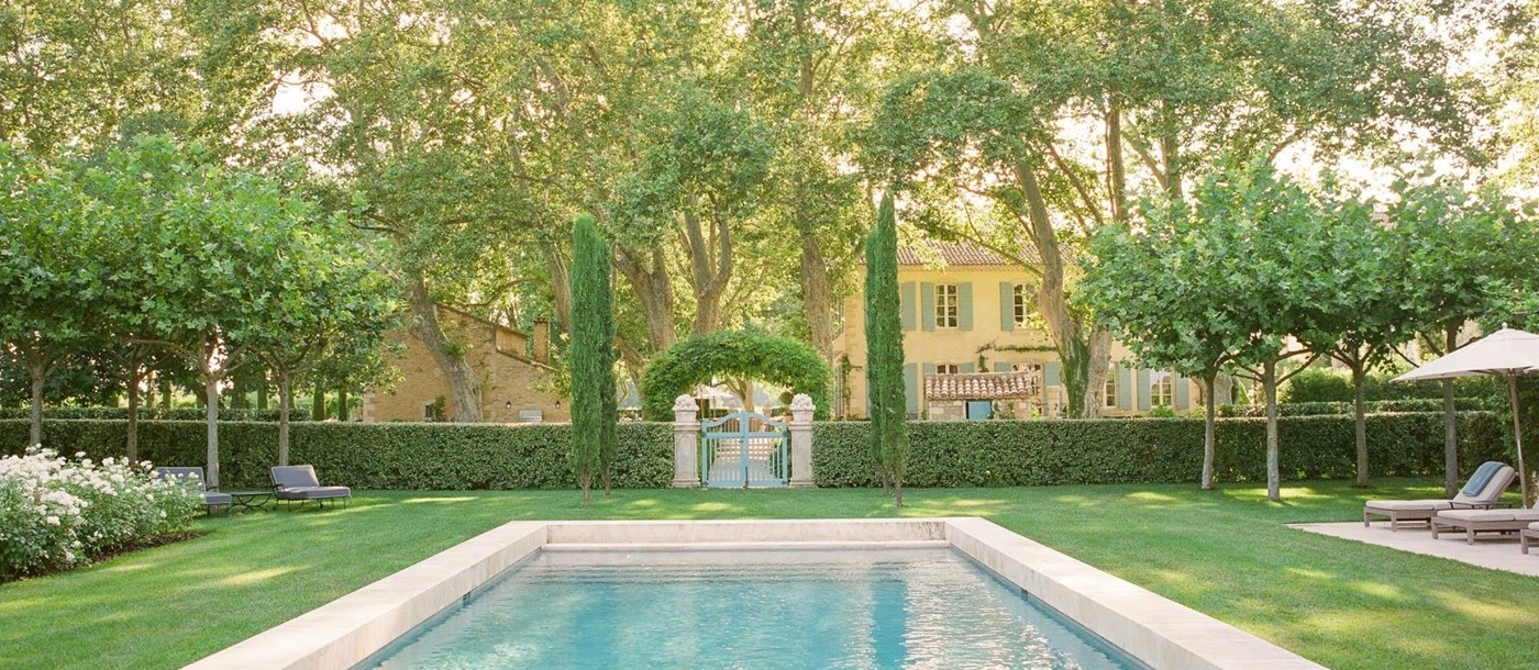 Gated pool area, lawn and patio with sun loungers and umbrellas at Mas de la Motte in Provence, France