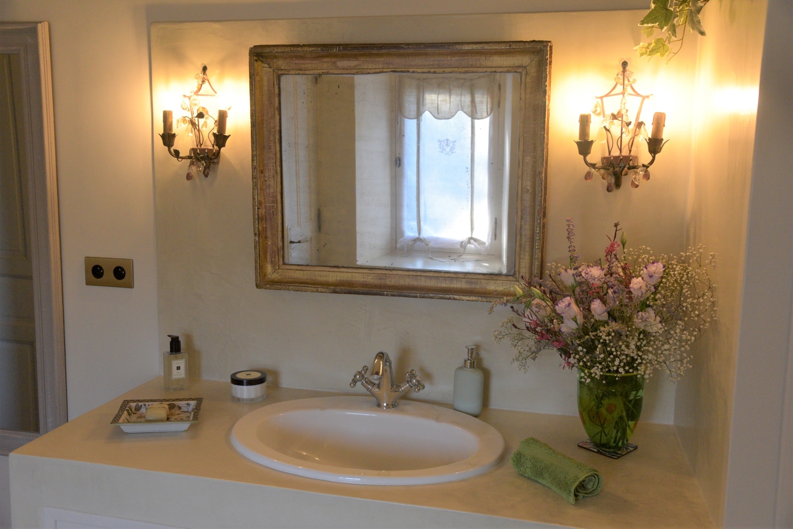 Bathroom with sink, flowers, mirror and lights at Mas des Cerisiers in Provence, France