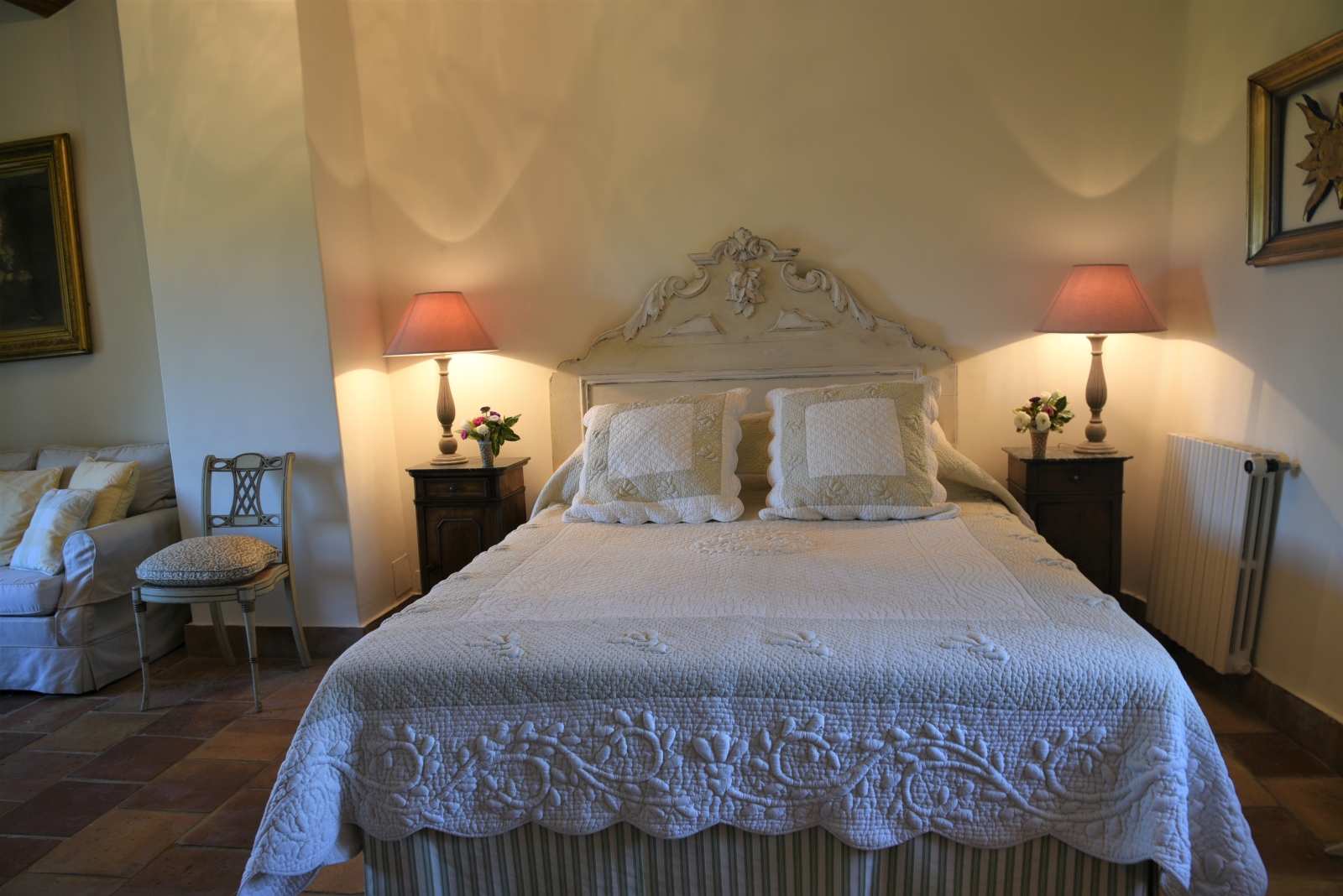 Bedroom with double bed, bedside tables, lamps, chair and sofa at Mas des Cerisiers in Provence, France