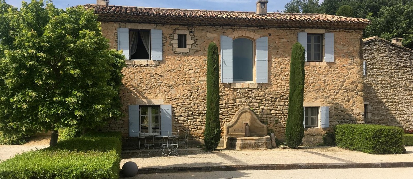 Facade, trees, hedges, boules court and dining table at Mas des Cerisiers in Provence, France