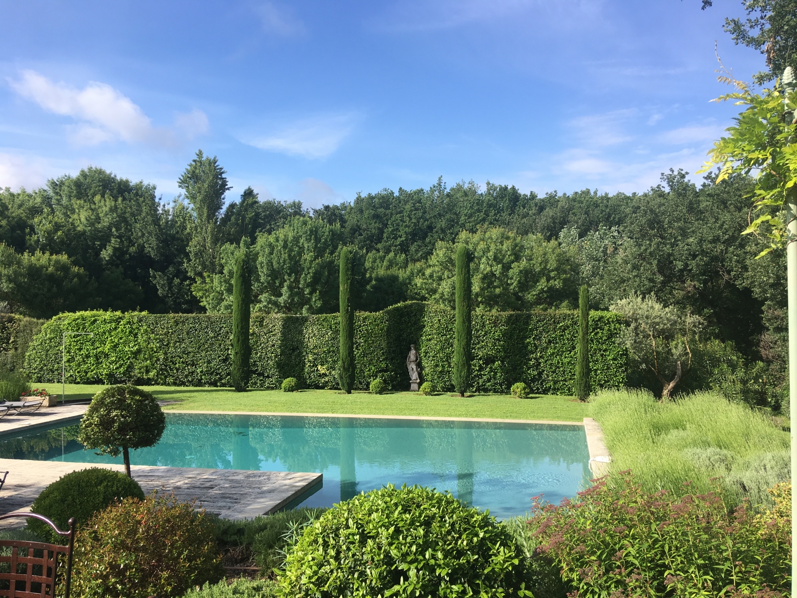 Garden with swimming pool, cypress trees, hedges and statue at Mas des Cerisiers in Provence, France