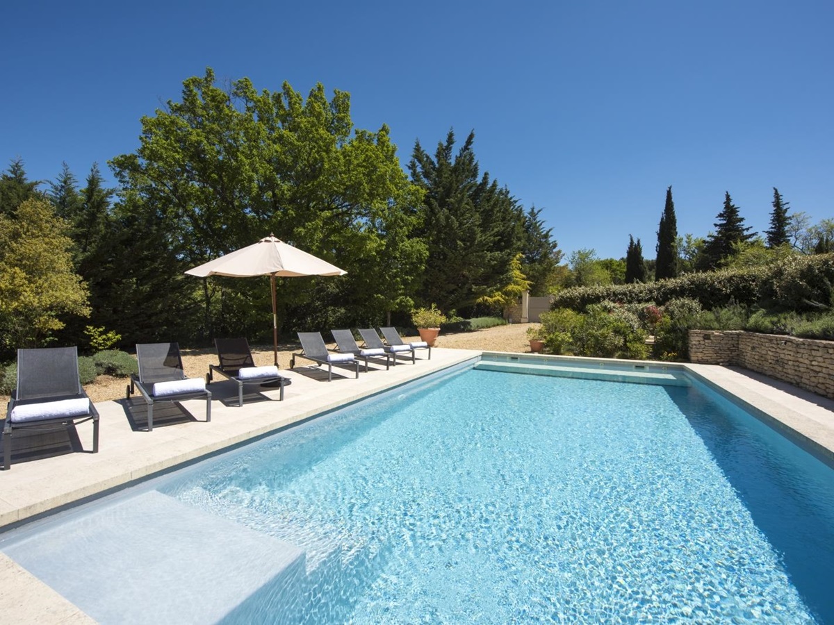 Pool and pool area with sun loungers, towels and umbrellas at Mas du Buis in Provence, France