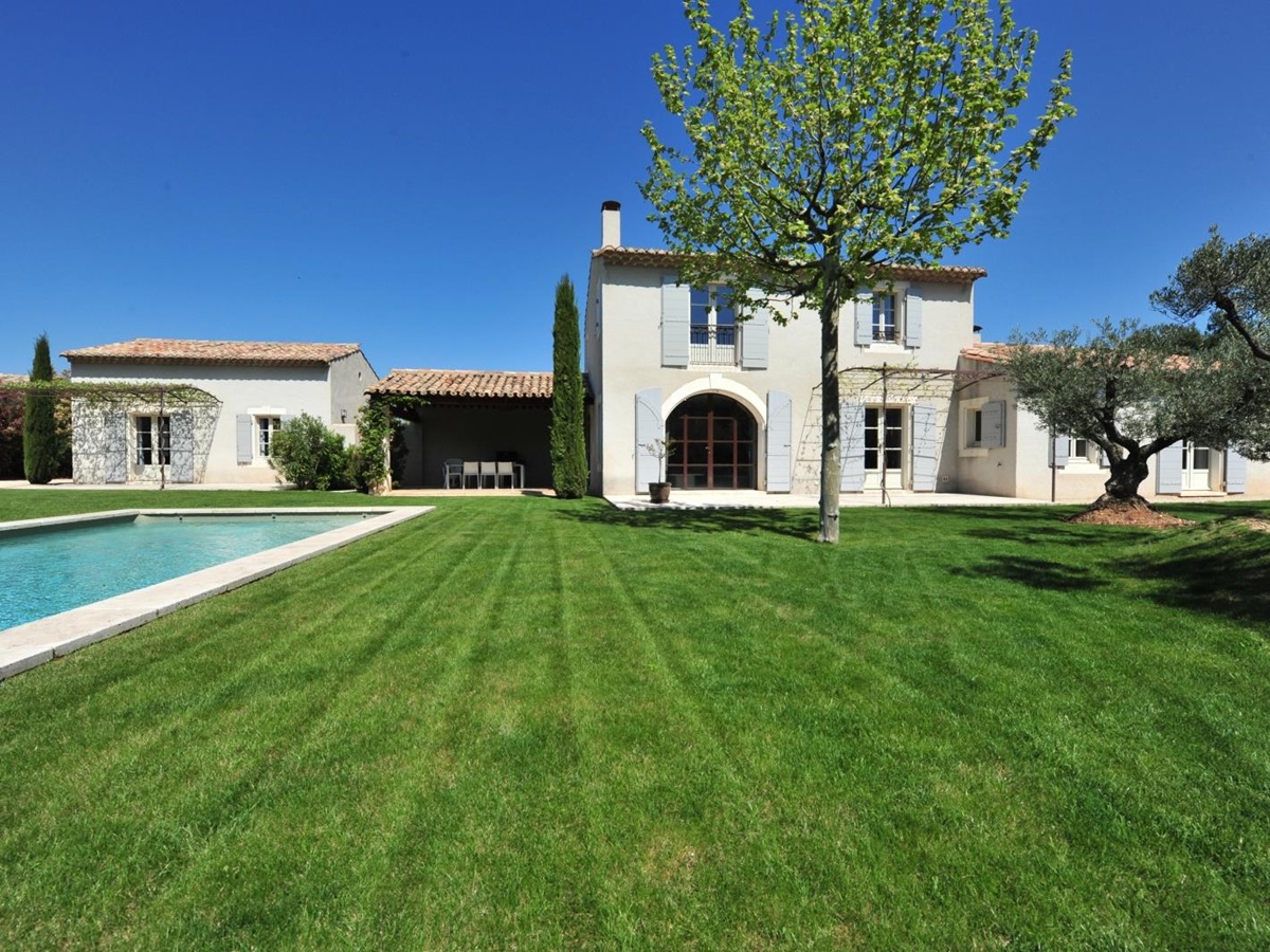 Green lawn with front of villa and side of pool at Mas Eygalieres in Provence
