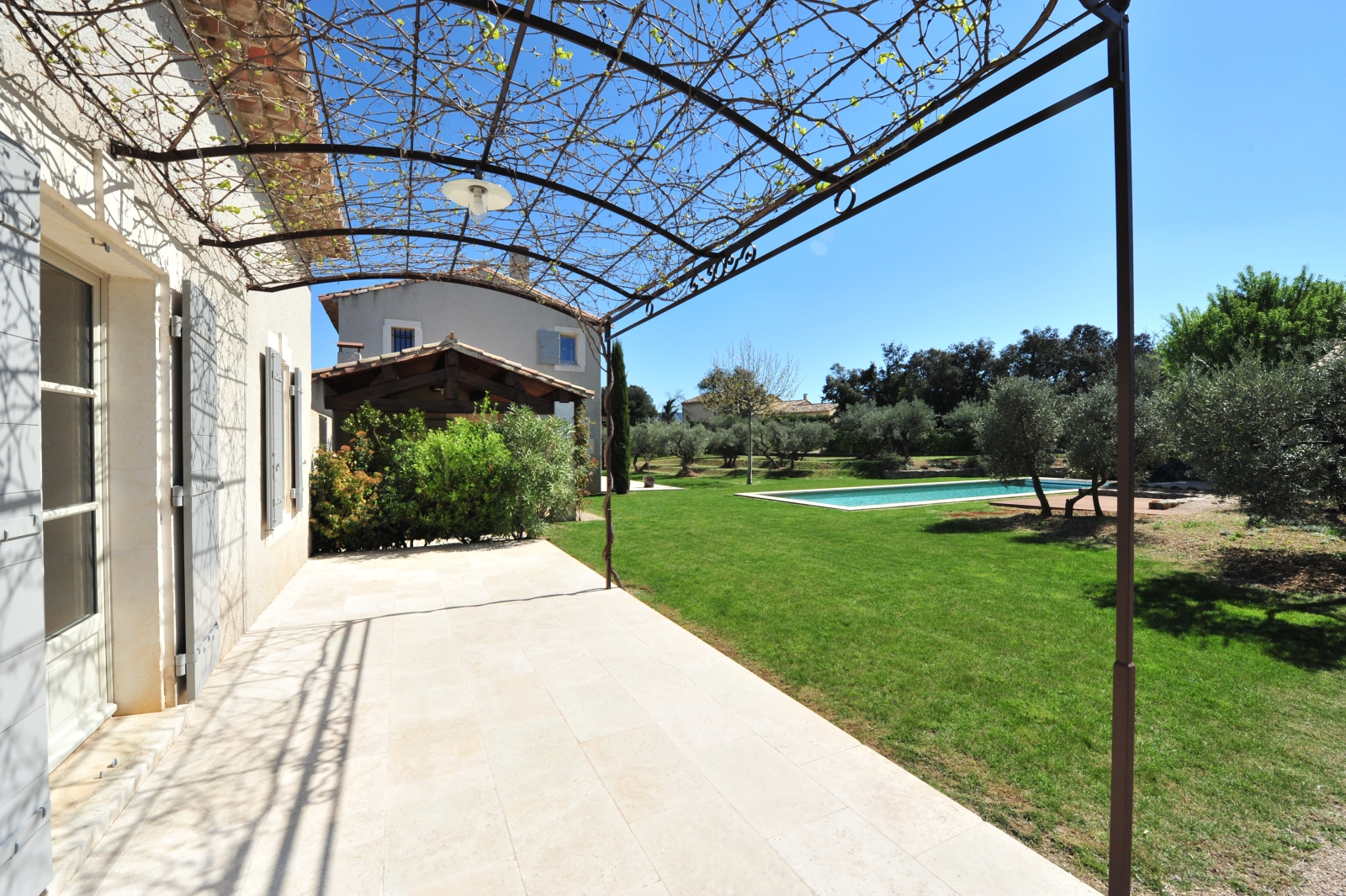 Covered pergola terrace with garden to the right at Mas Eygalieres in Provence