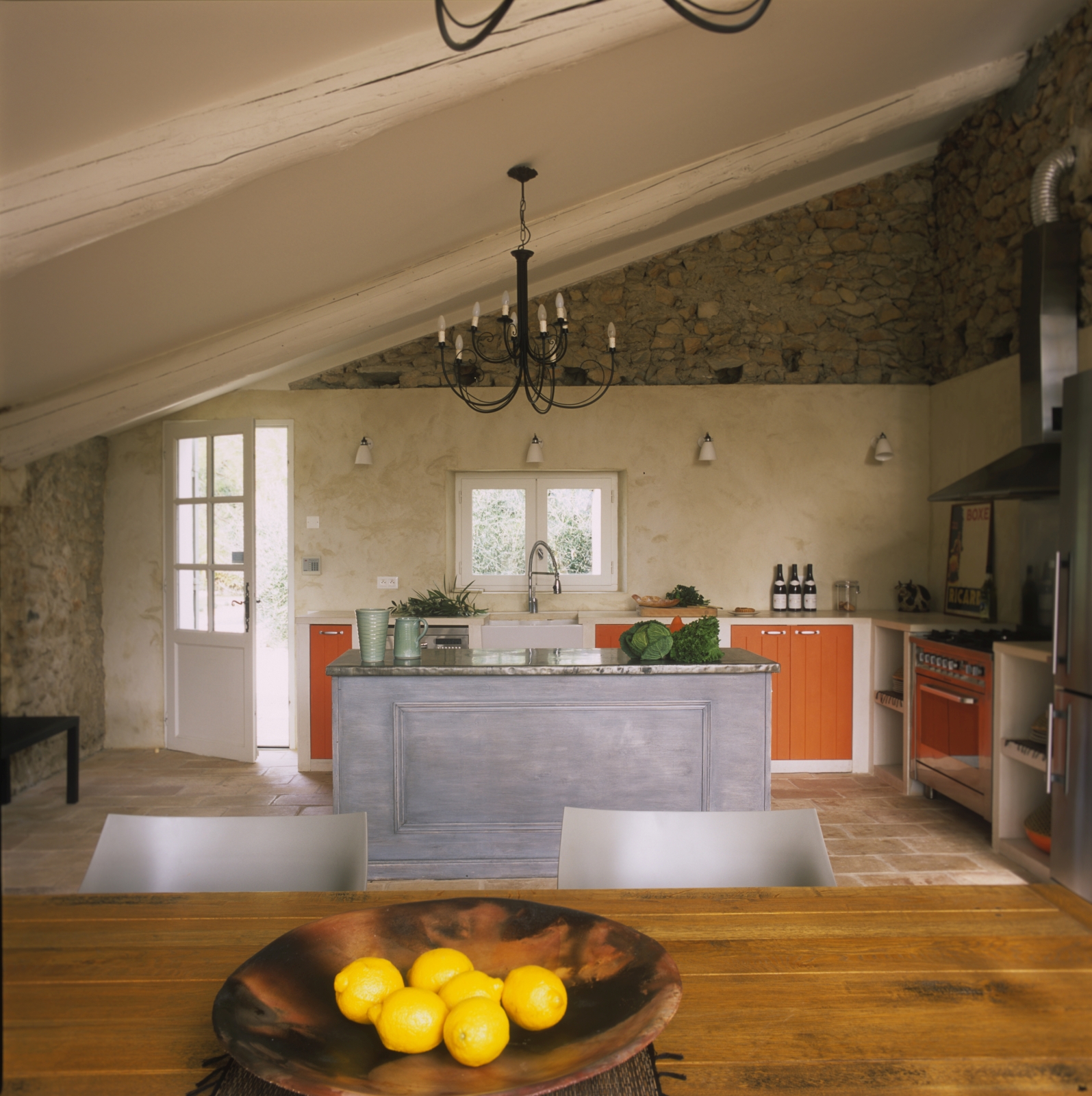 Kitchen with fresh food, island, hanging light and door at Mas Jaisses in Provence, France