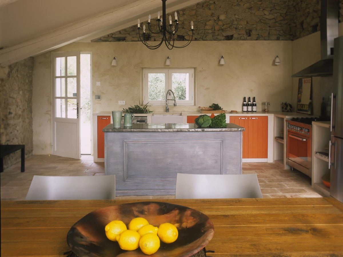 Kitchen with fresh food, island, hanging light and door at Mas Jaisses in Provence, France