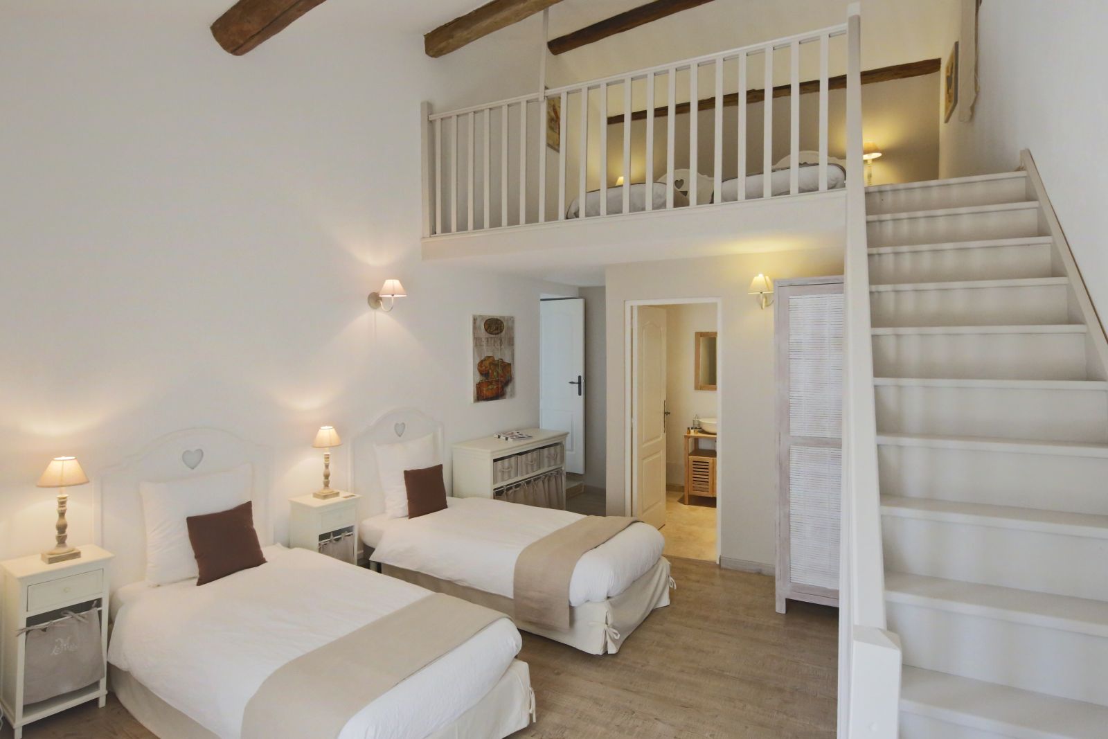 Bedroom with twin beds, ensuite bathroom and stairs to a mezzanine level with two more single beds at Villa Mas Peyre