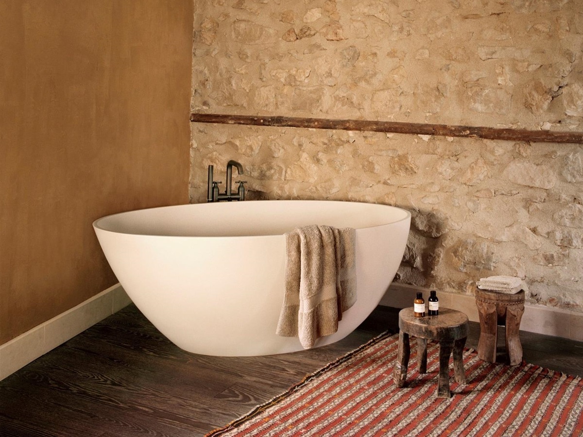 oval freestanding bathtub in the corner of a room with wooden floor in villa athena in provence, france