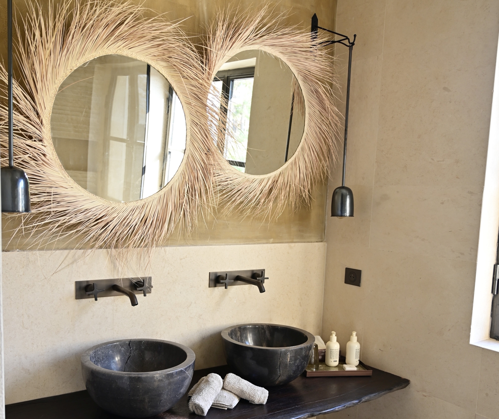 two round mirrors with grey marble wash basins underneath on a wooden shelf at villa athena in provence, france