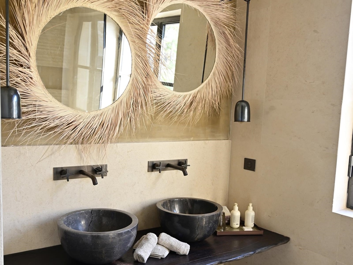 two round mirrors with grey marble wash basins underneath on a wooden shelf at villa athena in provence, france