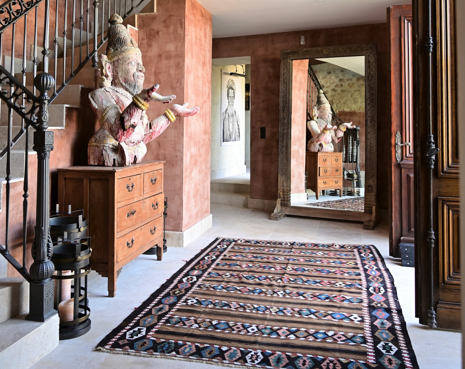 Hallway with buddha statue, drawers, patterned rug, candles, large mirror and staircase at Villa Athena in Provence, France