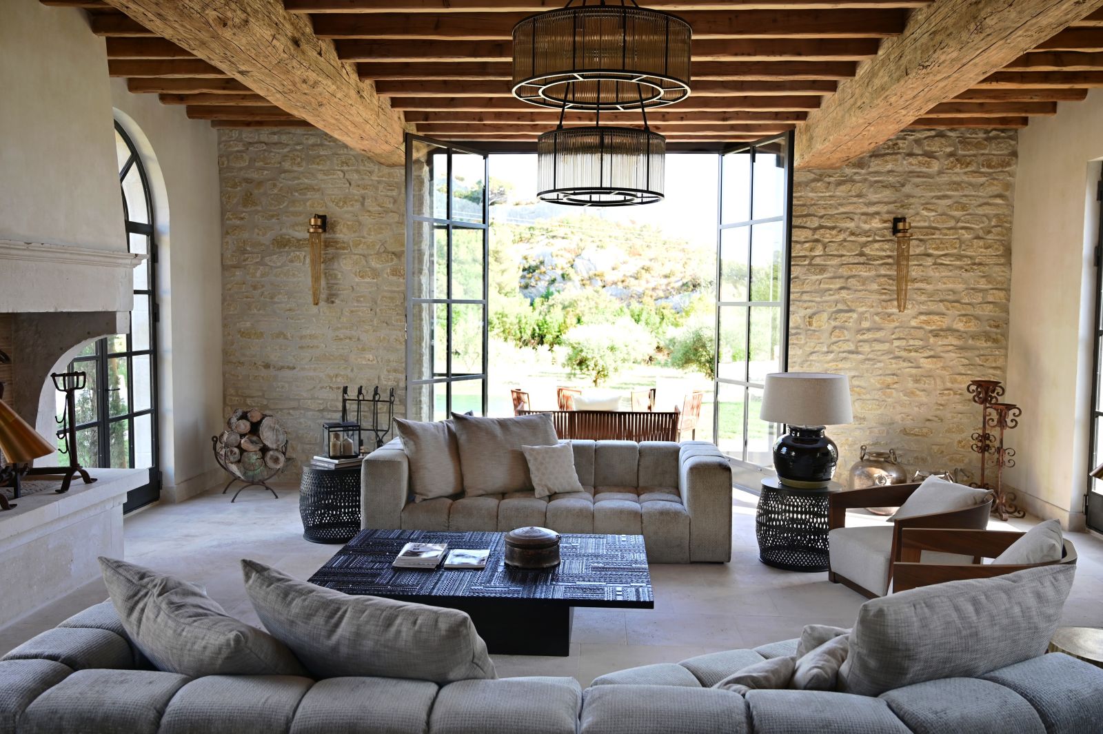 living area with two grey coloured sofas, coffee table and large open windows onto the garden at Villa Athena in Provence
