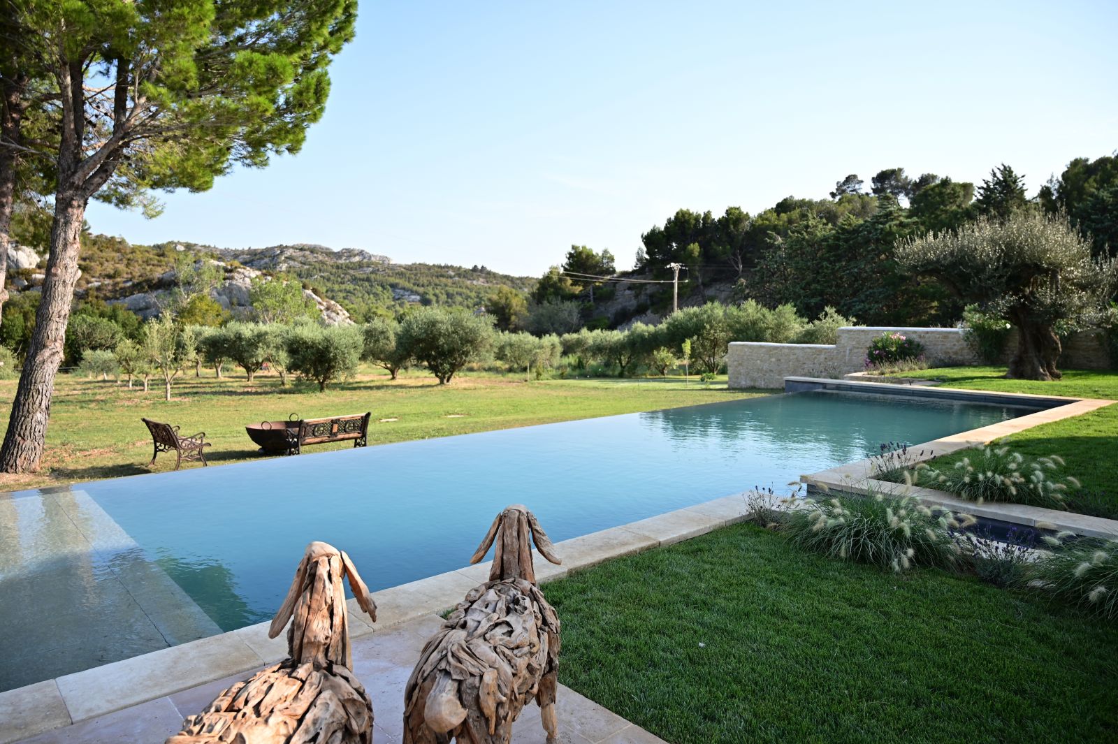 two carved wooden sheep overlooking the swimming pool and garden at Villa Athena in Provence 