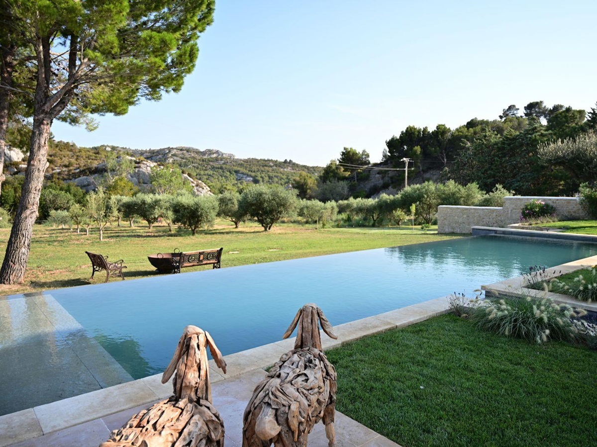 two carved wooden sheep overlooking the swimming pool and garden at Villa Athena in Provence