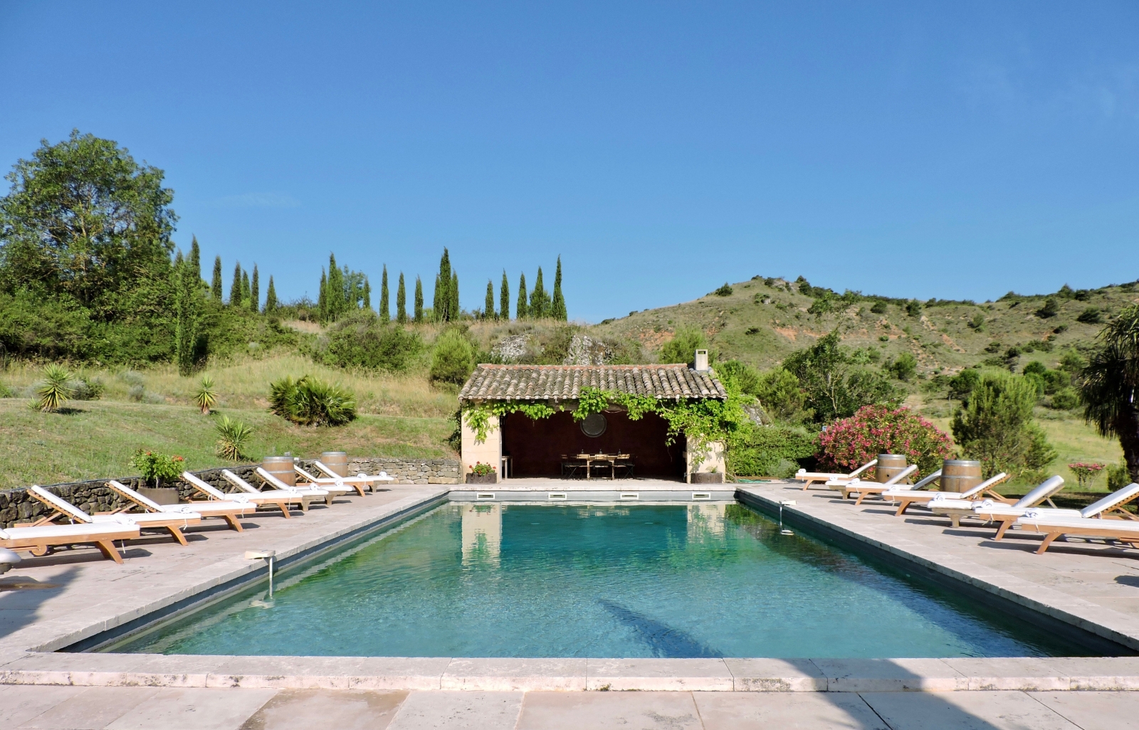 Pool and patio area with sun loungers and covered dining area at Domaine de Corbieres in South West France