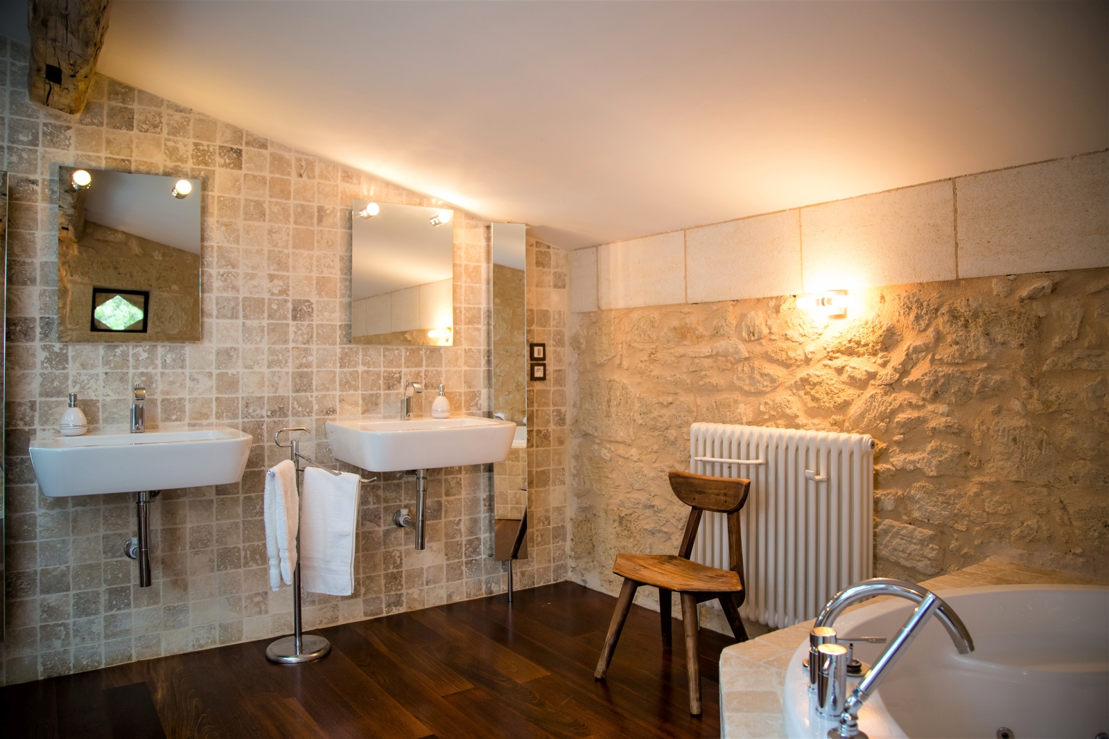 Bathroom with two sinks, two mirrors, chair, radiator and bathtub at La Colline Bleue in South West France