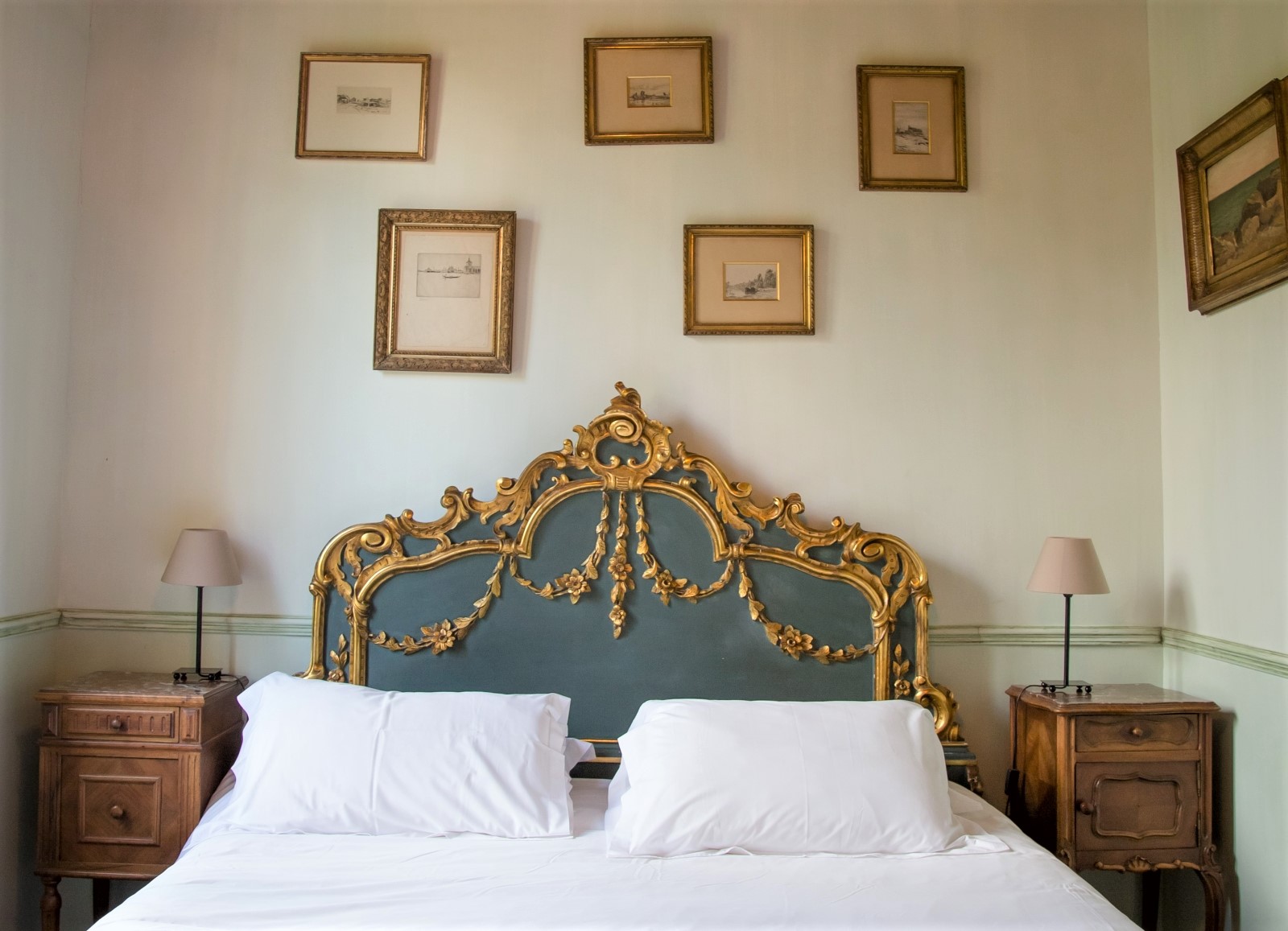 Bedroom with double bed, bedside tables, lamps and picture frames at La Colline Bleue in South West France