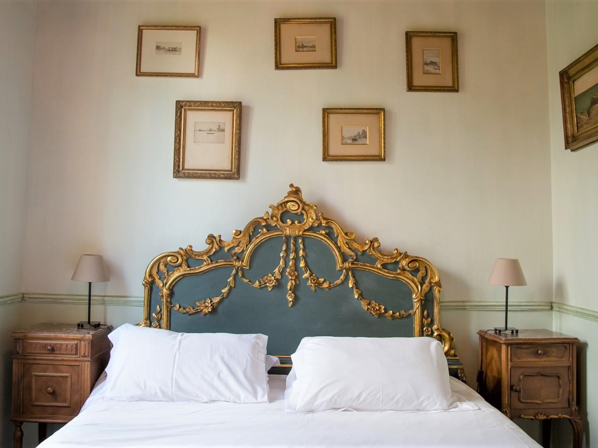 Bedroom with double bed, bedside tables, lamps and picture frames at La Colline Bleue in South West France