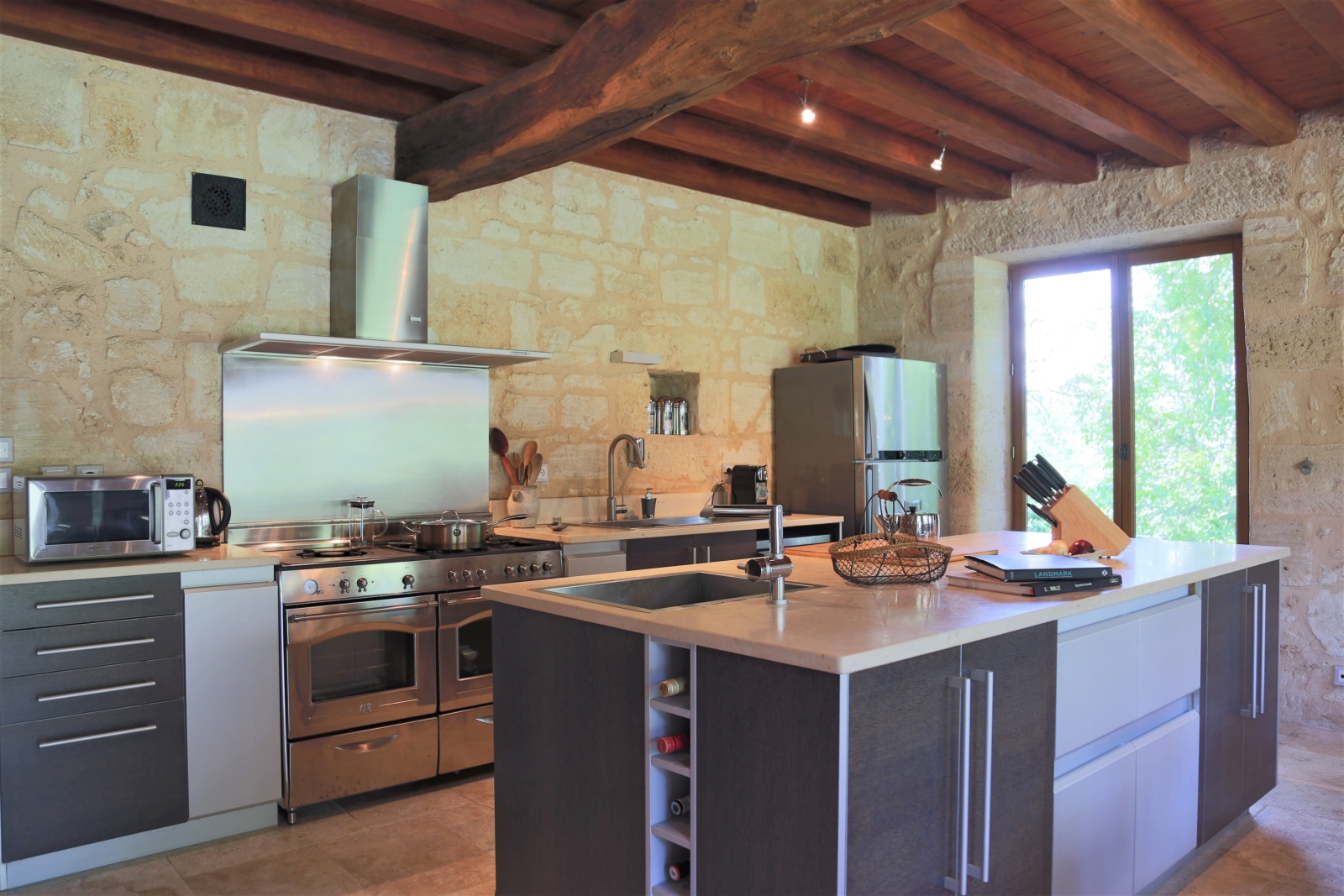 Kitchen with island, cookbooks, appliances and French doors at La Colline Bleue in South West France