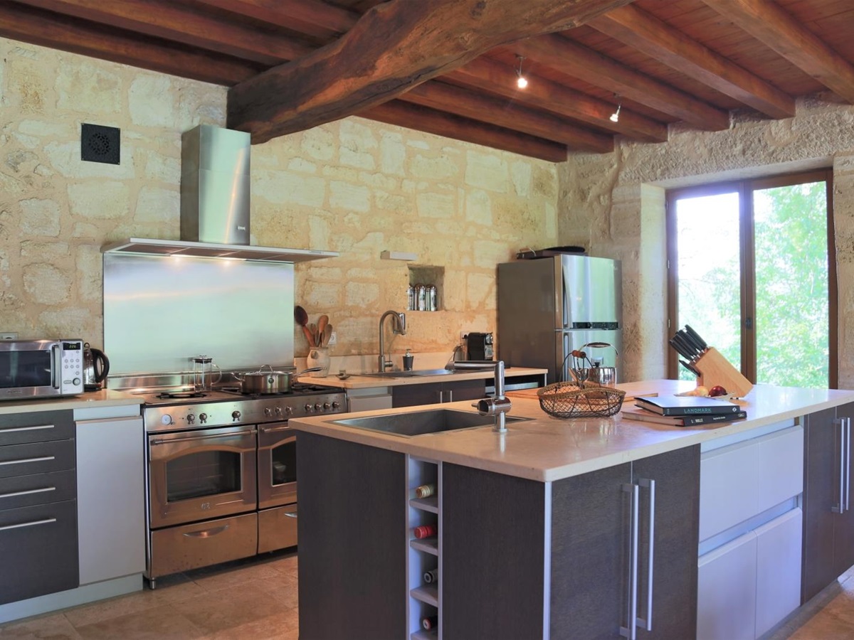 Kitchen with island, cookbooks, appliances and French doors at La Colline Bleue in South West France