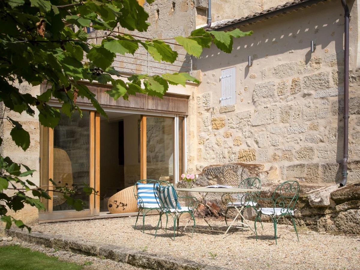 Patio with dining table, chairs and flowers at La Colline Bleue in South West France